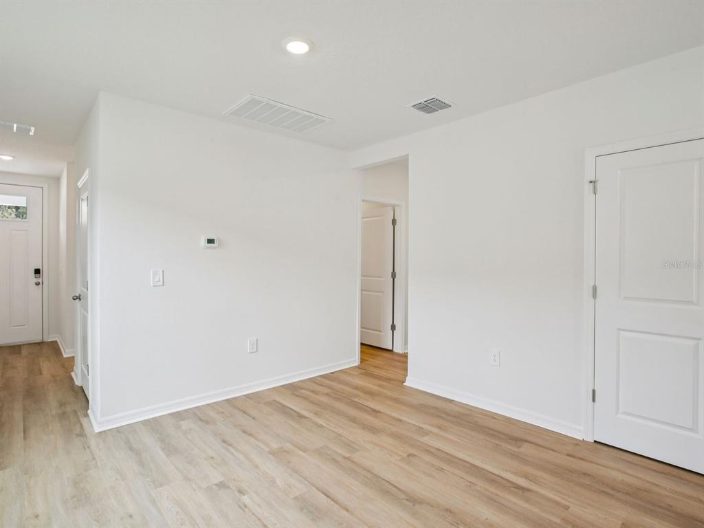 An empty room features light wood-look flooring, white walls, and several white interior doors — 7488 MIA VINE DRIVE, BROOKSVILLE, FL