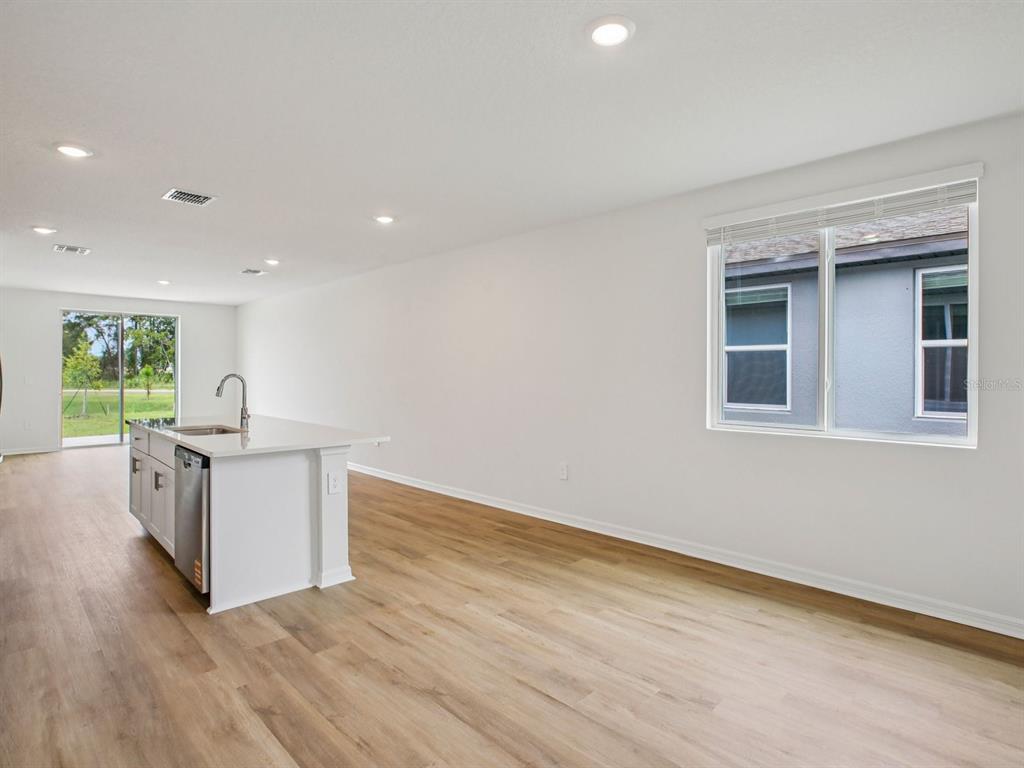 A kitchen island with a sink sits in a room with light wood-look flooring — 7488 MIA VINE DRIVE, BROOKSVILLE, FL
