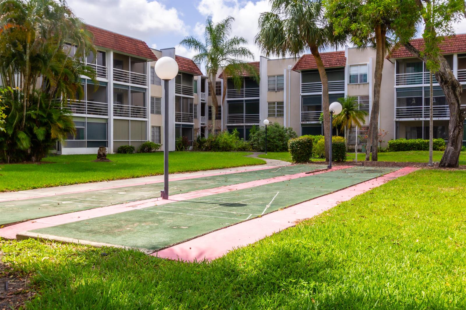 An outdoor shuffleboard court sits on a grassy lawn in front of a multi-story apartment building — 3531 Inverrary Drive # H406, Lauderhill FL 33319, LAUDERHILL, FL