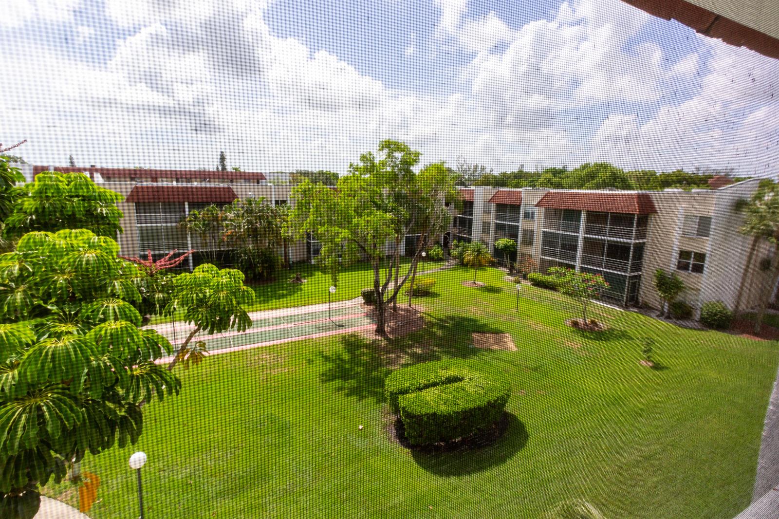 An elevated view of a grassy courtyard between apartment buildings with a shuffleboard court — 3531 Inverrary Drive # H406, Lauderhill FL 33319, LAUDERHILL, FL