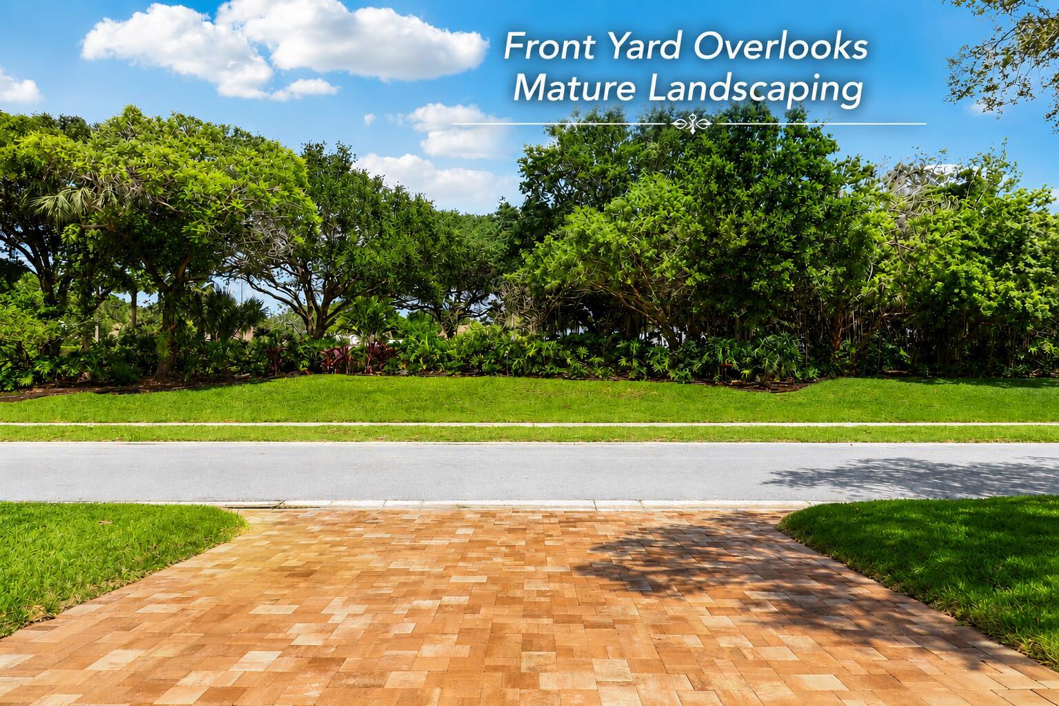 A paved driveway leads to a street with a grassy lawn and mature trees beyond — 154 Sandbar Drive, Jupiter FL 33477, JUPITER, FL