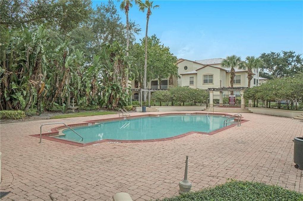 A rectangular swimming pool sits on a brick patio surrounded by trees and apartment buildings — 822 CAMARGO WAY UNIT 208, ALTAMONTE SPRINGS, FL