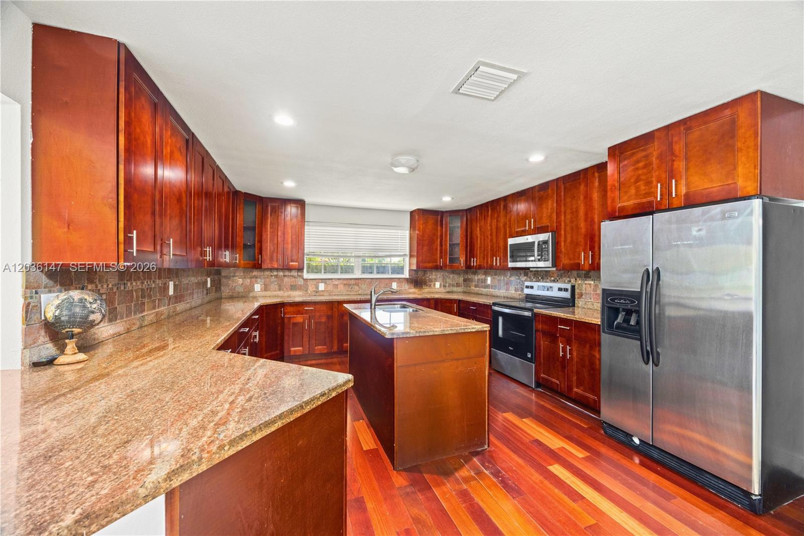 A kitchen features dark wood cabinets, granite countertops, stainless steel appliances, and hardwood flooring — 230 NE 5th Ave, Dania Beach FL 33004, DANIA BEACH, FL