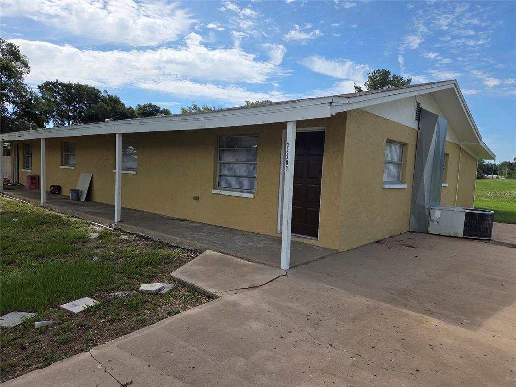 A yellow single-story house with a covered porch and a concrete driveway — 38300 HENRY DRIVE, ZEPHYRHILLS, FL
