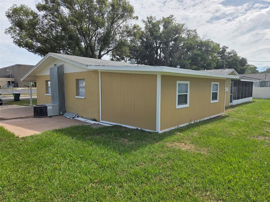 The exterior of a single-story house features yellow siding, a concrete patio, and a lawn — 38300 HENRY DRIVE, ZEPHYRHILLS, FL