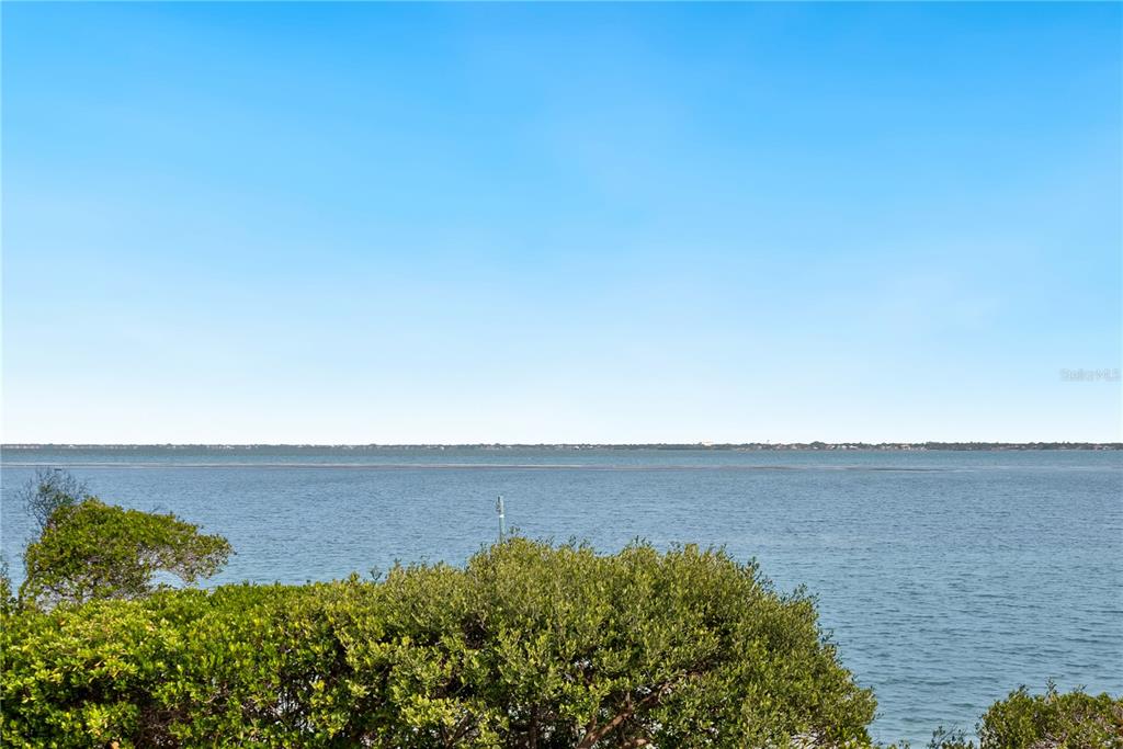 A view of a calm body of water framed by green trees under a clear sky — 340 GULF OF MEXICO DRIVE UNIT 115, LONGBOAT KEY, FL