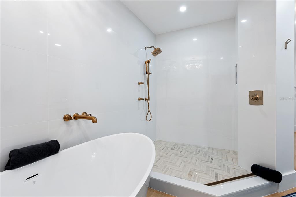 A modern bathroom features a white freestanding tub and a walk-in shower with gold fixtures — 340 GULF OF MEXICO DRIVE UNIT 115, LONGBOAT KEY, FL