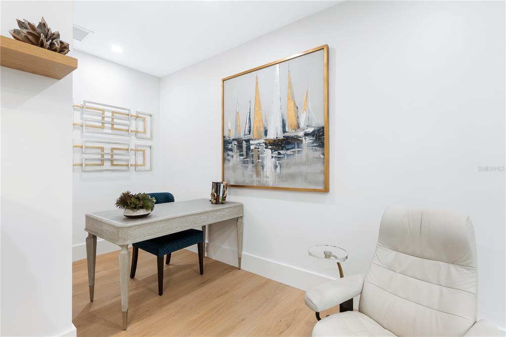 A home office features a desk, a blue chair, a white armchair, and sailboat wall art — 340 GULF OF MEXICO DRIVE UNIT 115, LONGBOAT KEY, FL