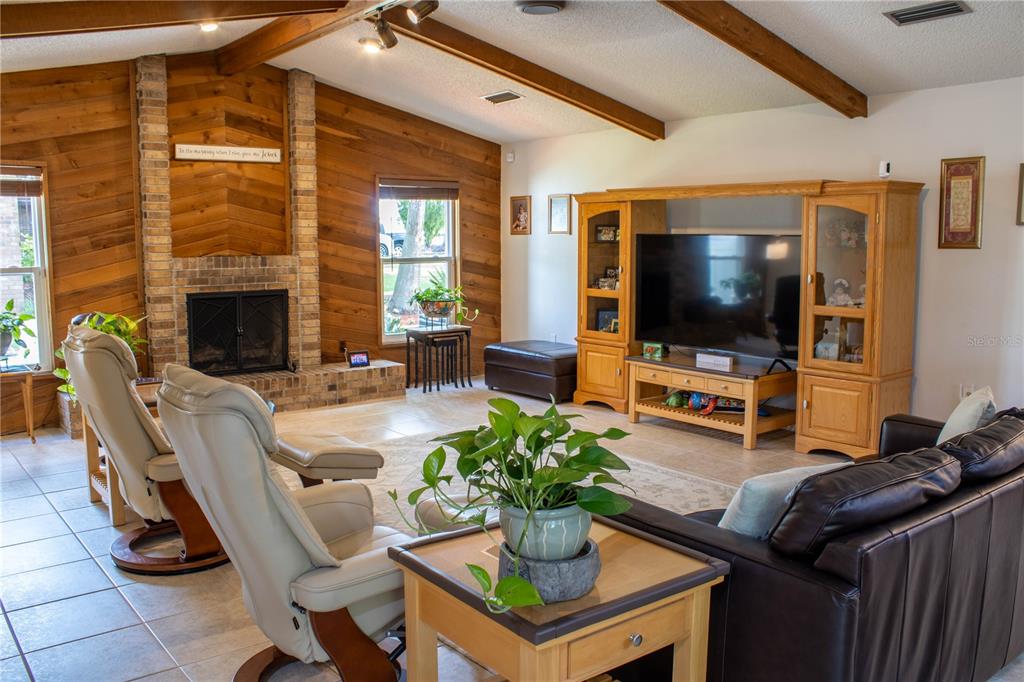 A living room features wood-paneled walls, a brick fireplace, vaulted ceilings, and tile flooring — 5456 HOUSTON DRIVE, LAKELAND, FL
