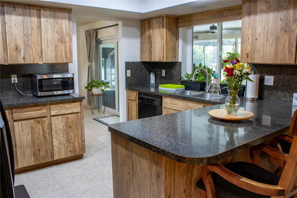 A kitchen features wood cabinets, dark granite countertops, a breakfast bar, and a sliding glass door — 5456 HOUSTON DRIVE, LAKELAND, FL