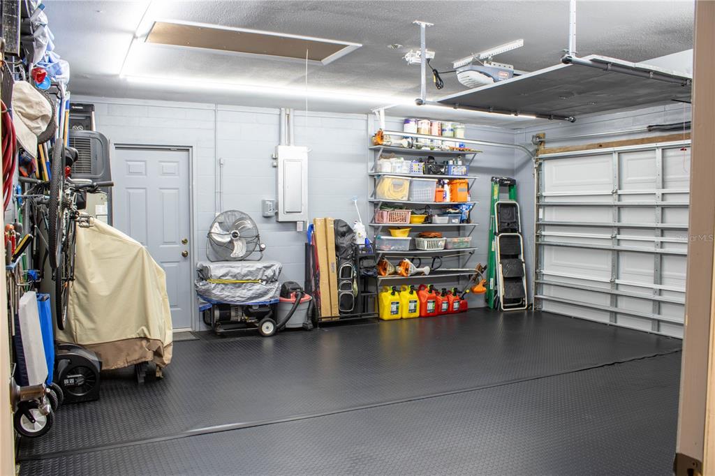 A garage with gray block walls, a black rubber floor, and metal storage shelving — 5456 HOUSTON DRIVE, LAKELAND, FL