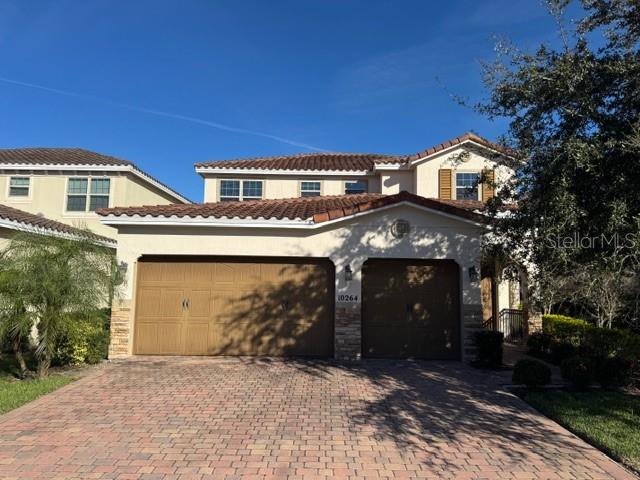 A two-story house with a tiled roof and a paved driveway features a three-car garage — 10264 HENBURY STREET, ORLANDO, FL