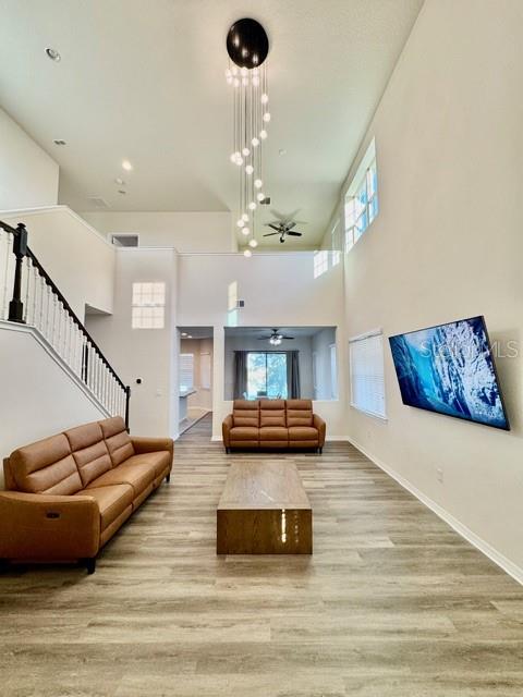 A living room features a high ceiling, a modern chandelier, and two brown leather sofas — 10264 HENBURY STREET, ORLANDO, FL