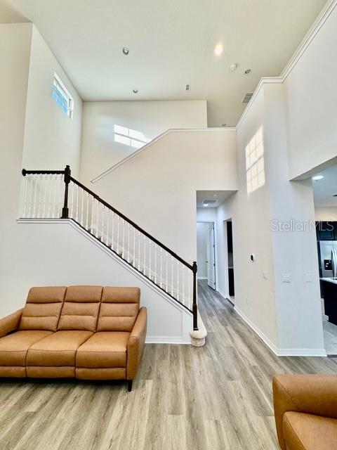 A living room features a tan leather sofa, light wood flooring, and a staircase — 10264 HENBURY STREET, ORLANDO, FL