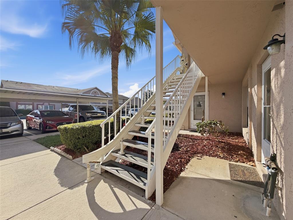 An exterior view of a building entrance with a white staircase leading to an upper level — 4833 MYRTLE OAK DRIVE UNIT 12, NEW PORT RICHEY, FL