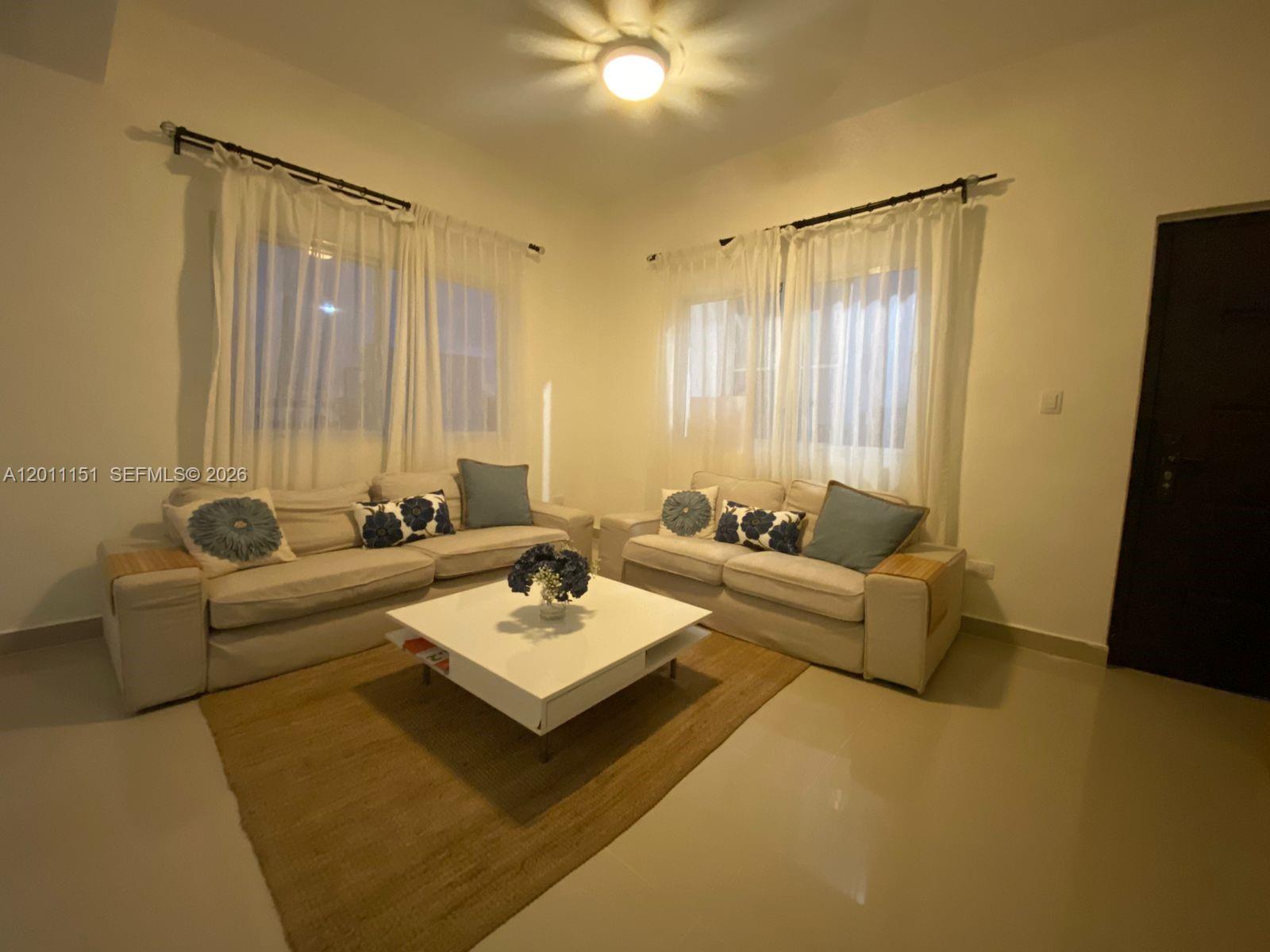 A living room features two beige sofas, a white coffee table, and sheer window curtains — M.71 Ciudad La Palma Dominican Republic, FL