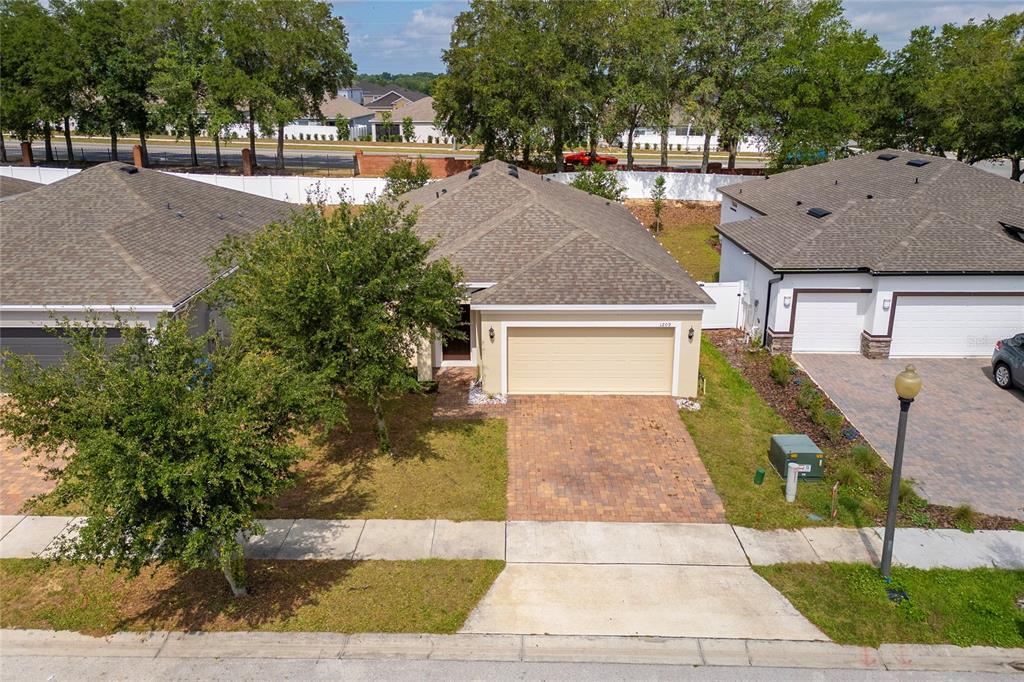 An aerial view of a single-story house with a tan garage and brick driveway — 1209 STRATTON AVENUE, GROVELAND, FL