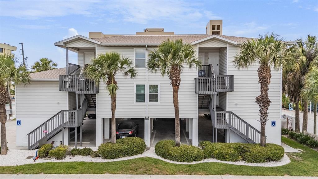 A two-story, light-colored building with elevated living areas, exterior staircases, and ground-level parking — 1500 GULF BOULEVARD UNIT 204B, INDIAN ROCKS BEACH, FL