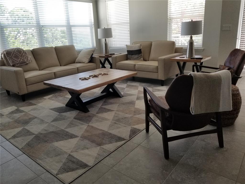 A living room features a beige sofa and loveseat, a wooden coffee table, and patterned rug — 7710 34TH AVENUE W UNIT 303, BRADENTON, FL