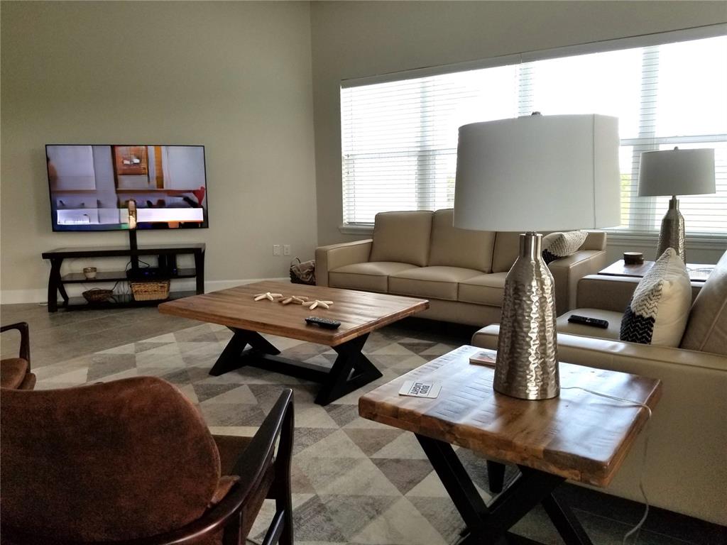 A living room features a beige sofa, wooden coffee table, and a television on a stand — 7710 34TH AVENUE W UNIT 303, BRADENTON, FL