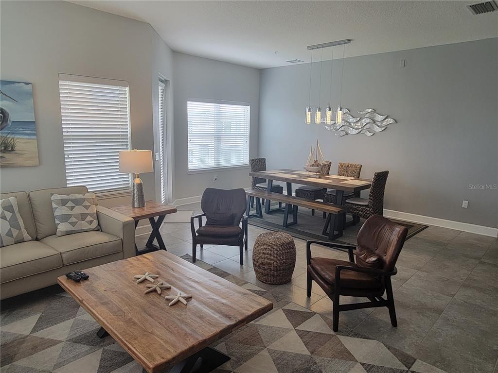 A living and dining area features tile floors, a wooden coffee table, and coastal decor — 7710 34TH AVENUE W UNIT 303, BRADENTON, FL