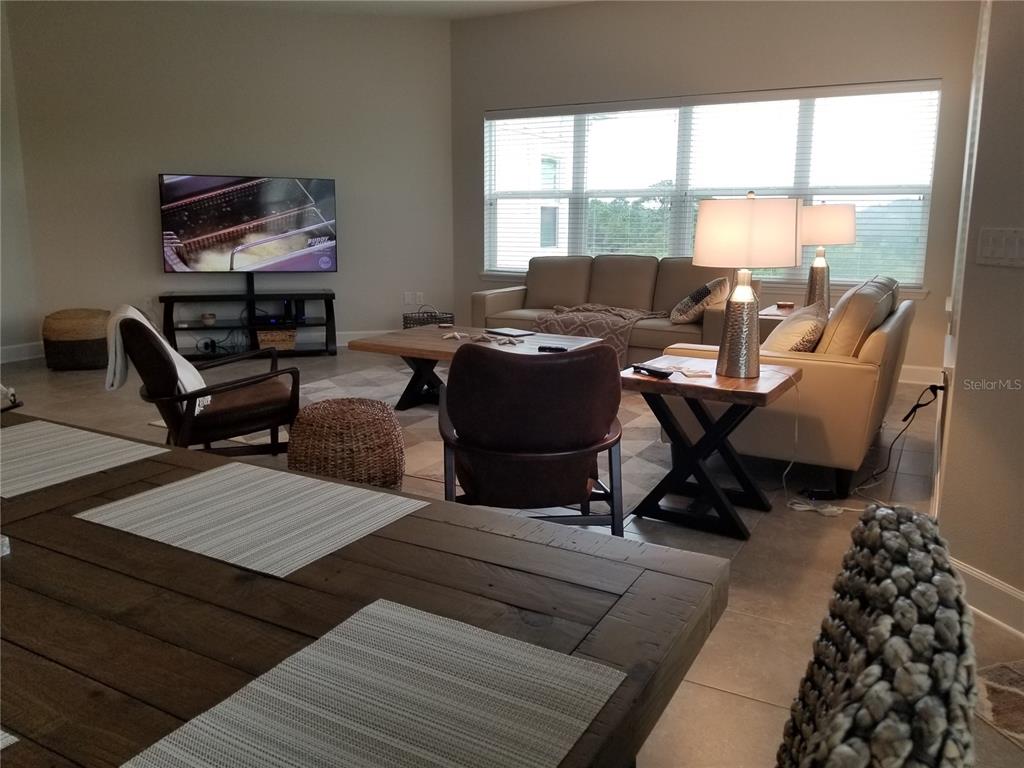 A living room features a beige sofa, two armchairs, a wooden coffee table, and a television — 7710 34TH AVENUE W UNIT 303, BRADENTON, FL