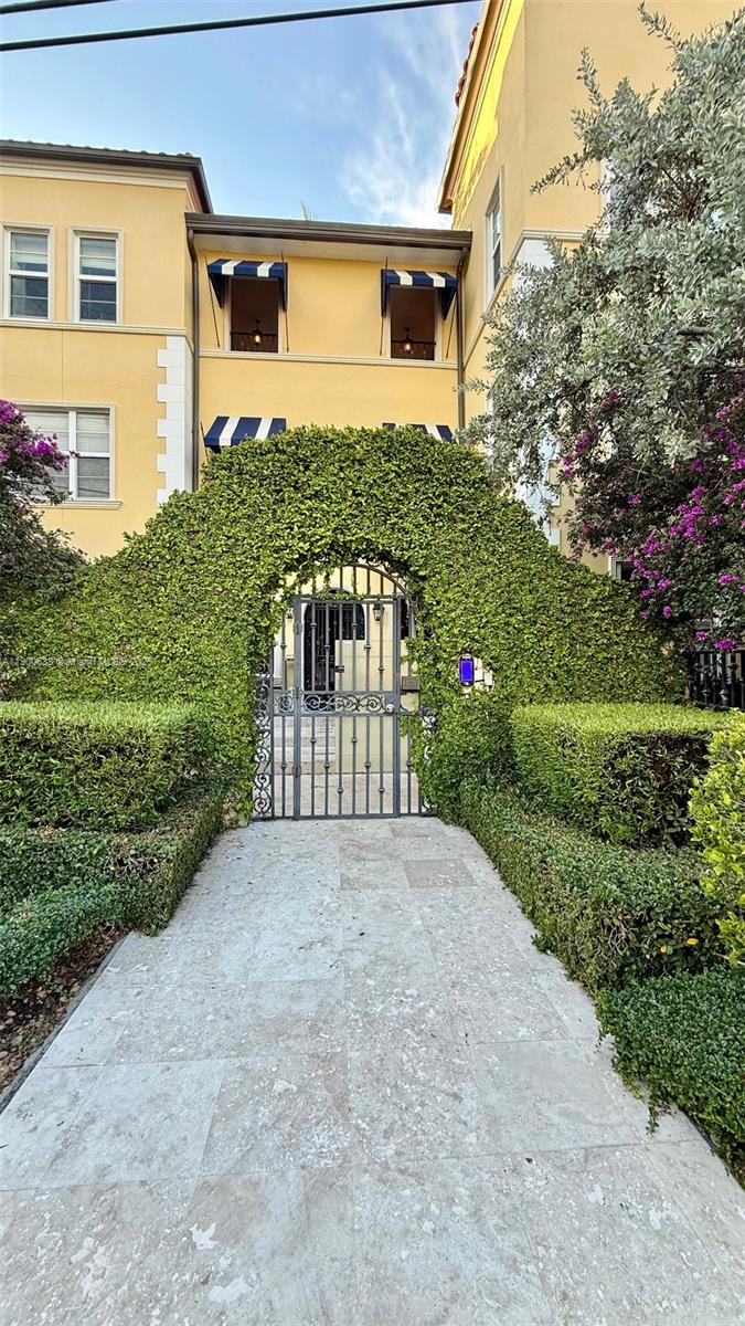 A stone walkway leads to a metal gate framed by a large, ivy-covered archway — 4812 Pine Tree Dr # 204, Miami Beach FL 33140, MIAMI BEACH, FL