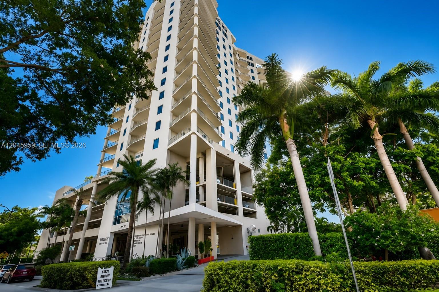 A tall, white residential high-rise building stands surrounded by palm trees under a bright sky — 10 SW South River Dr # 1708, Miami FL 33130, MIAMI, FL