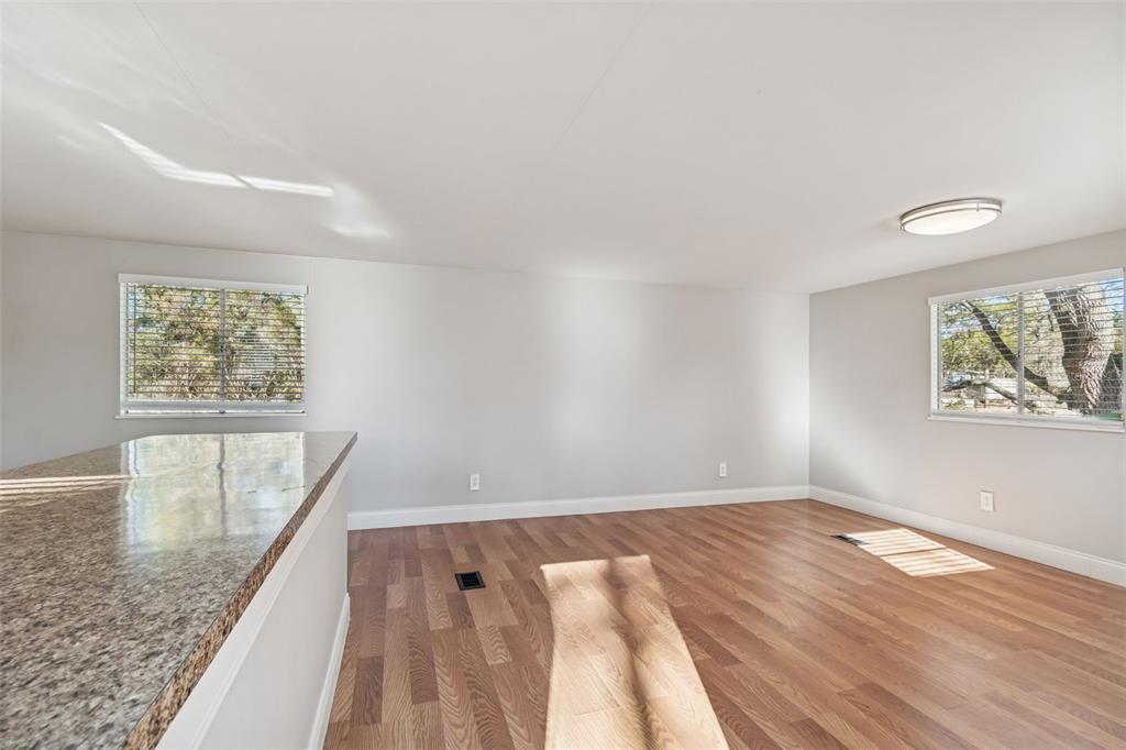 An empty room features light wood-look flooring, white walls, two windows, and a granite countertop — 5464 S WILSON POINT, HOMOSASSA, FL
