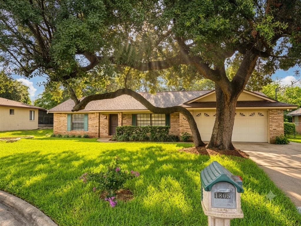 A single-story brick house with a large tree in the front yard and a mailbox — 1805 EXMORE AVENUE, DELTONA, FL