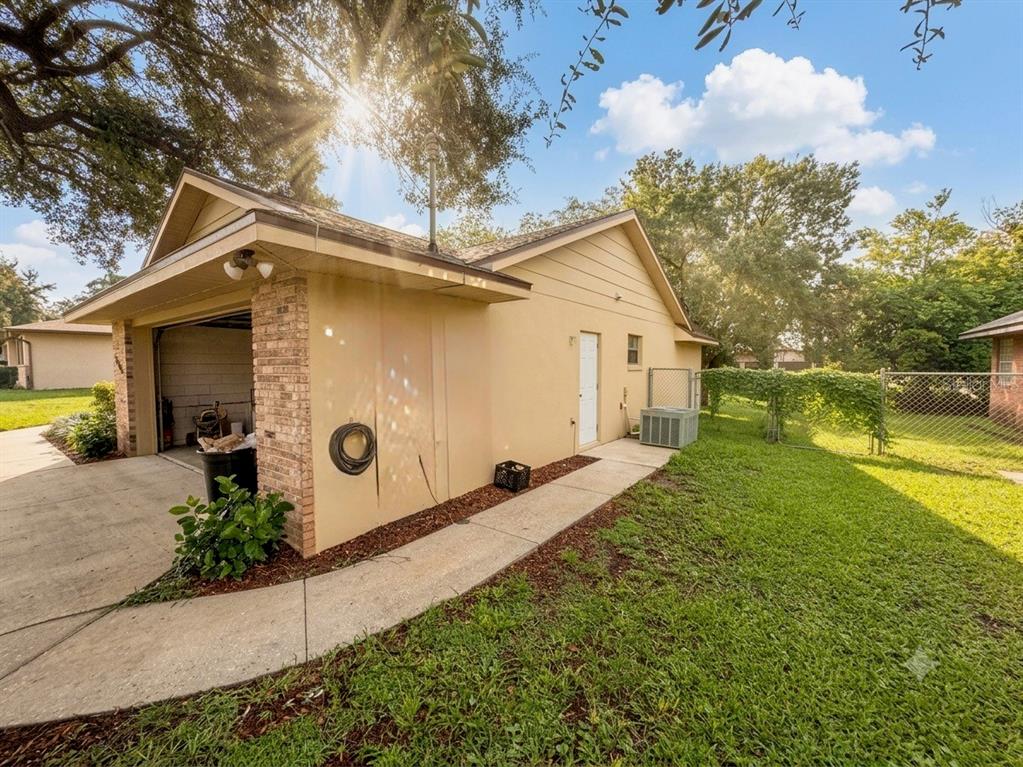 A detached garage with a side door, concrete walkway, and a grassy backyard — 1805 EXMORE AVENUE, DELTONA, FL