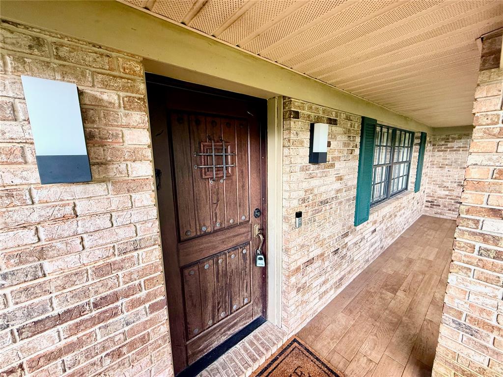 A brick exterior home features a wooden front door with a metal grille and window — 1805 EXMORE AVENUE, DELTONA, FL