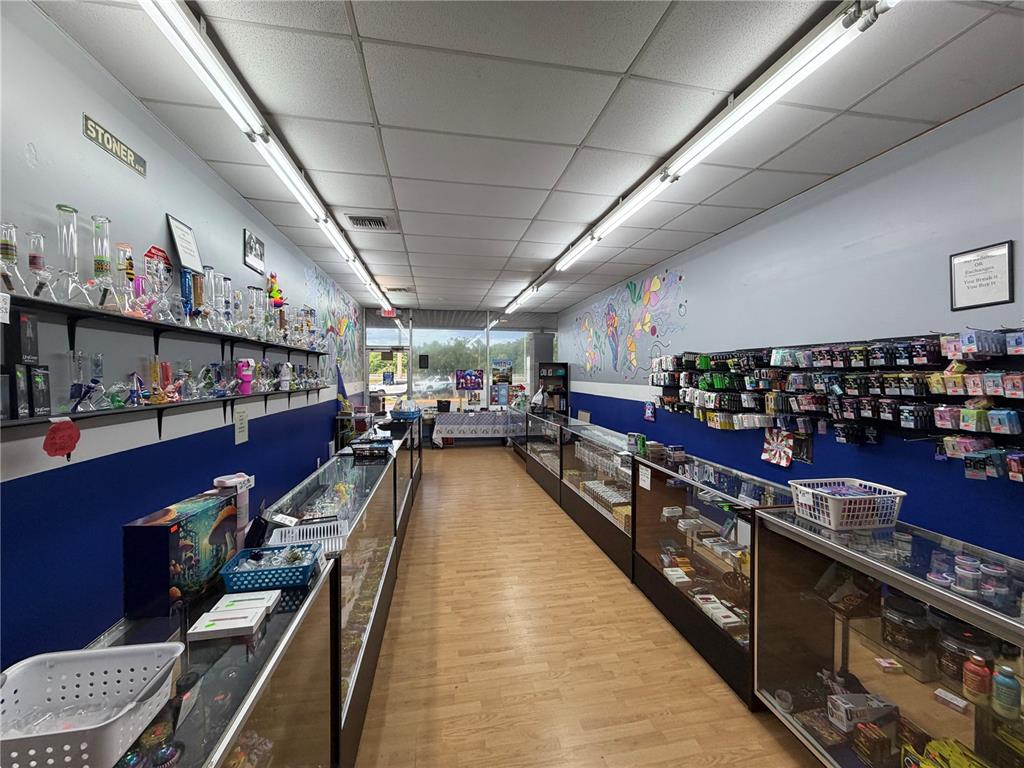 A retail smoke shop features glass display cases, wall-mounted shelves of pipes, and wood flooring — 11582 N WILLIAMS STREET, DUNNELLON, FL