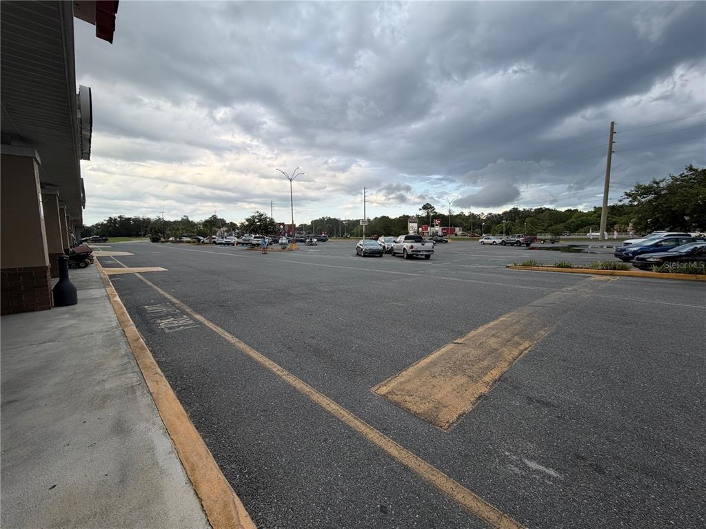A wide, paved parking lot sits in front of a commercial building under a cloudy sky — 11582 N WILLIAMS STREET, DUNNELLON, FL