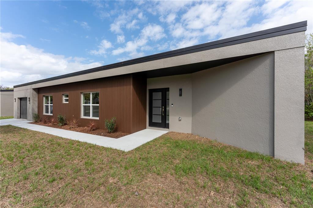 The exterior of a modern single-story house features brown corrugated siding and gray stucco walls — 457 RIVERVIEW AVENUE, SANFORD, FL