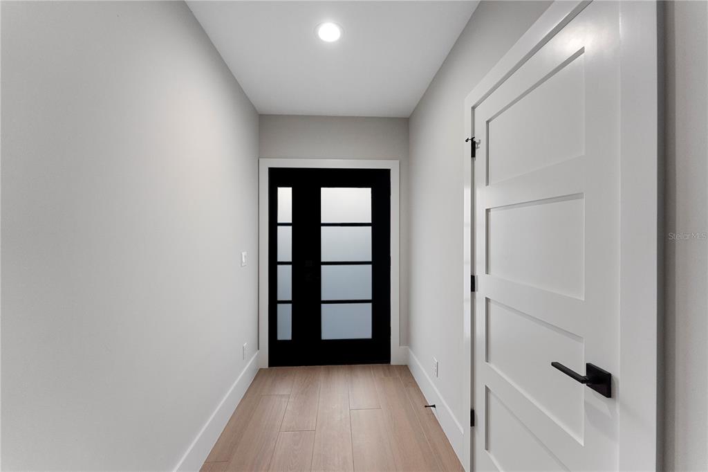 A hallway features light wood flooring, white walls, a black front door, and a white door — 457 RIVERVIEW AVENUE, SANFORD, FL
