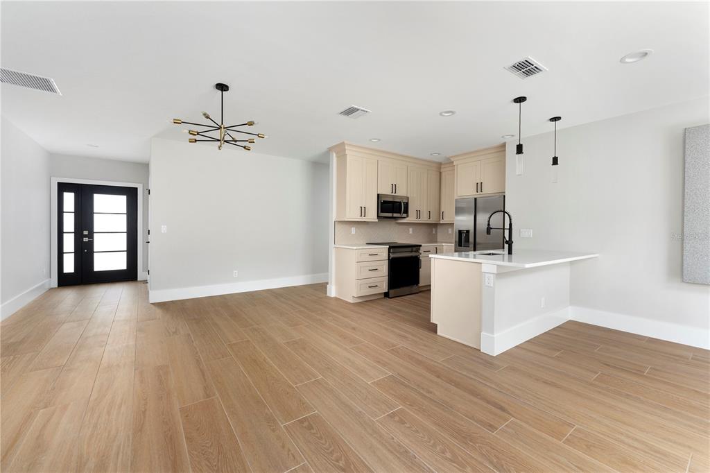 A kitchen with light-colored cabinets and a peninsula opens into a dining area with wood-look flooring — 457 RIVERVIEW AVENUE, SANFORD, FL