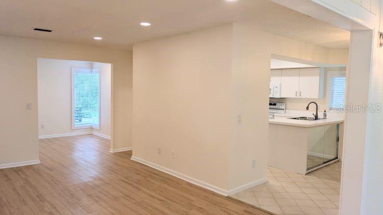 An interior view showing a living area with wood-look flooring leading to a kitchen — 10 MASTERS COURT, PALM COAST, FL
