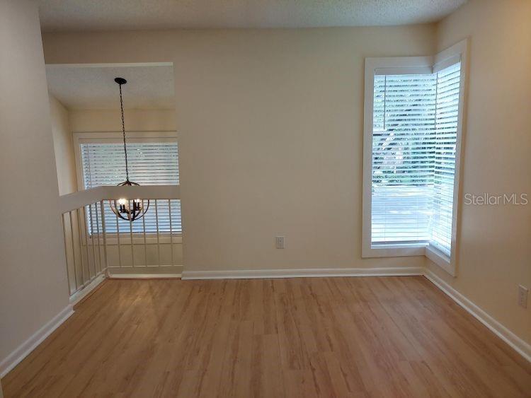 An empty room with light wood-look flooring, a bay window, and a hanging light fixture — 10 MASTERS COURT, PALM COAST, FL