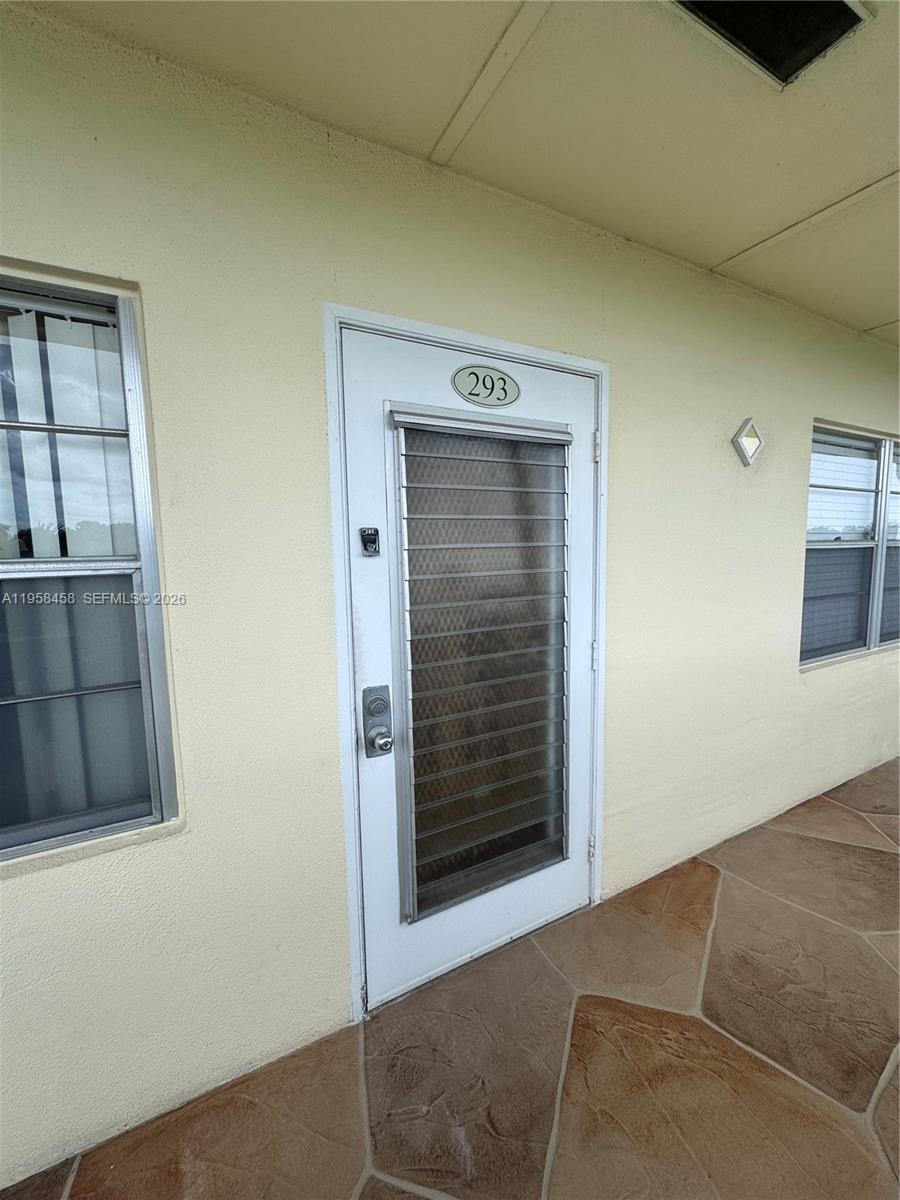 A white door with a louvered glass insert is labeled with the number 293 — 293 Dorset # G, Boca Raton FL 33434, BOCA RATON, FL