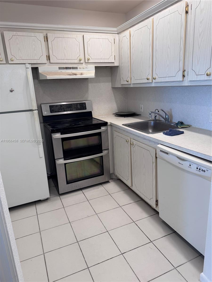 A kitchen features white cabinets, a double-oven range, a dishwasher, and a tiled floor — 293 Dorset # G, Boca Raton FL 33434, BOCA RATON, FL