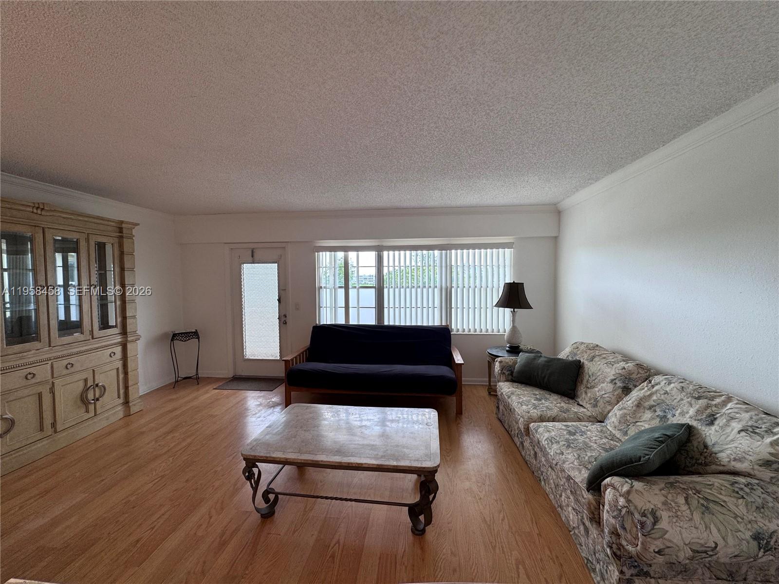 A living room features a floral sofa, a dark futon, and a wooden cabinet — 293 Dorset # G, Boca Raton FL 33434, BOCA RATON, FL