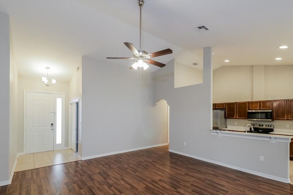An open-concept living area features wood-look flooring, a ceiling fan, and an adjacent kitchen — 426 DISSTON AVENUE, CLERMONT, FL