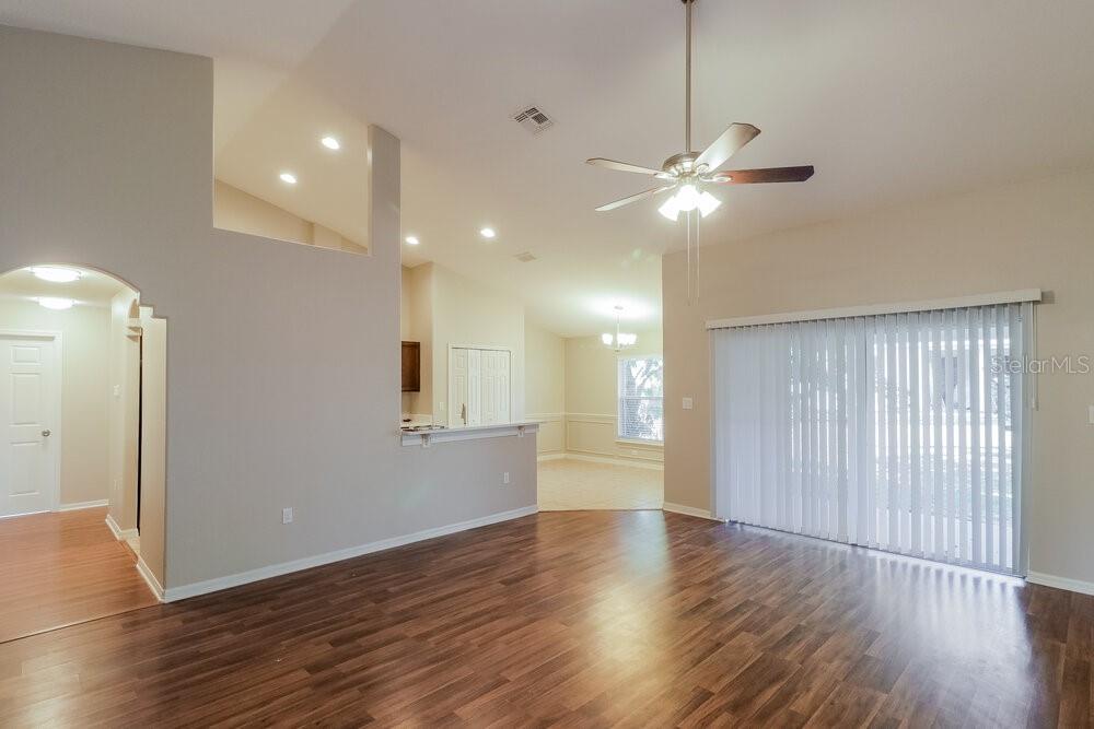 A living room with wood-look flooring, a ceiling fan, and a sliding glass door — 426 DISSTON AVENUE, CLERMONT, FL