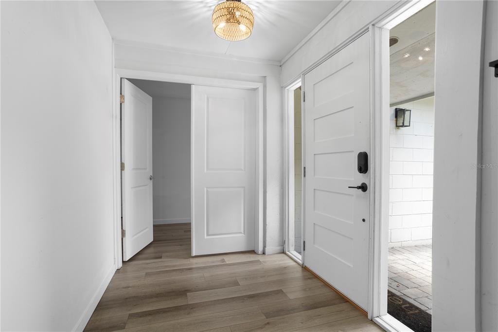 An entryway features light wood-look flooring, white walls, a modern light fixture, and two doors — 2412 GRANDVIEW AVENUE, SANFORD, FL