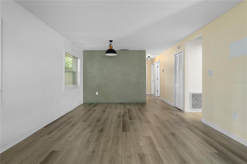 An empty room features light wood-look flooring, a sage green accent wall, and a pendant light — 2412 GRANDVIEW AVENUE, SANFORD, FL