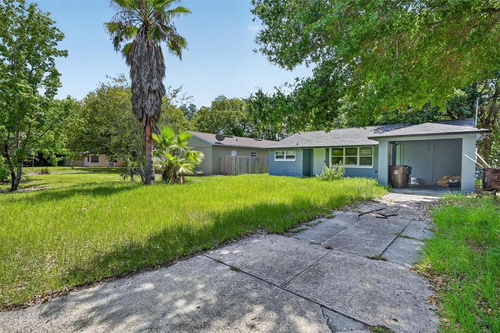 A blue house with a carport and a large grassy yard under a sunny sky — 116 S GLENWOOD AVENUE, ORLANDO, FL