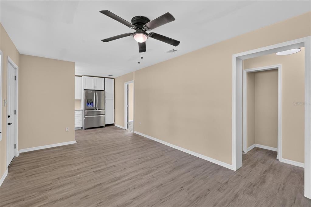 A room with light beige walls, wood-look flooring, a ceiling fan, and an open kitchen — 116 S GLENWOOD AVENUE, ORLANDO, FL