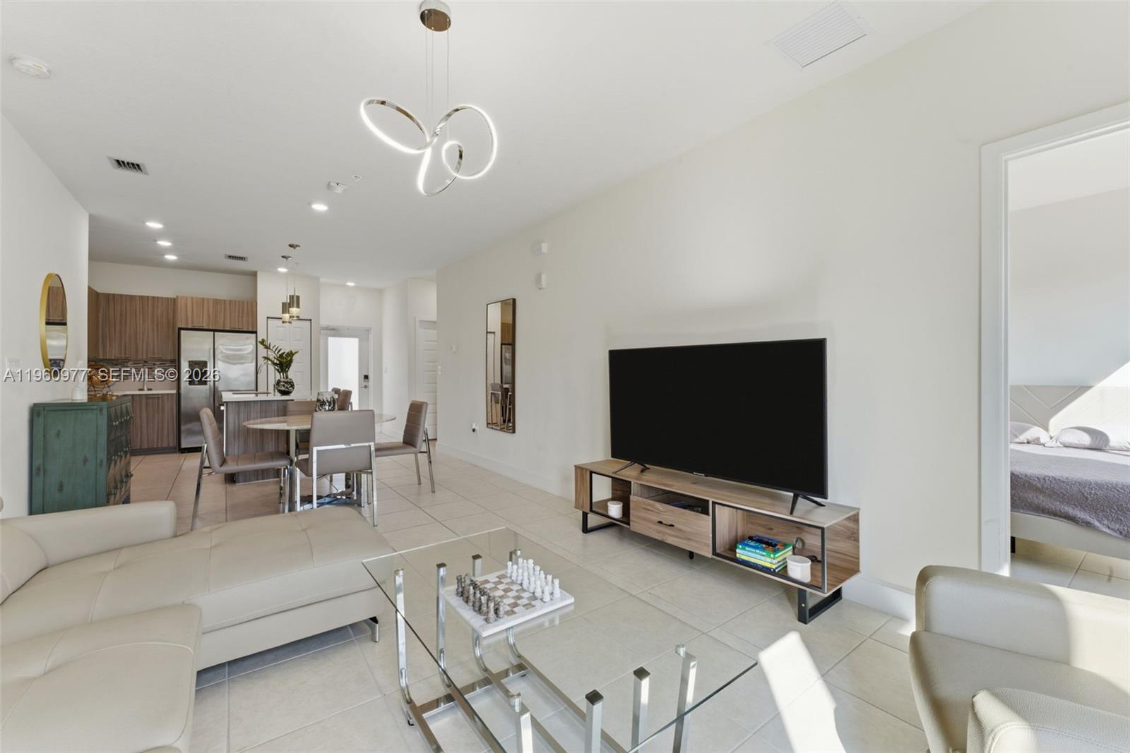 A modern living room features a television console, glass coffee table, and open-concept kitchen — 8301 NW 41st St # 407, Doral FL 33166, DORAL, FL