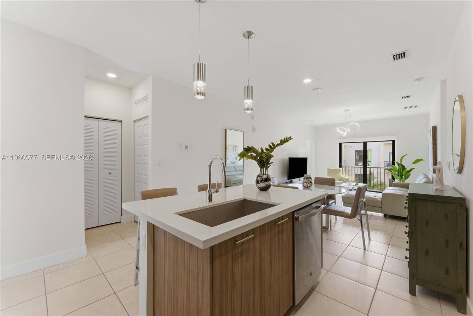 A modern kitchen island with a sink and dishwasher overlooks an open-concept living area — 8301 NW 41st St # 407, Doral FL 33166, DORAL, FL